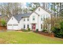 Beautiful two-story home featuring a red front door, well-maintained lawn, and a three-car garage at 4057 Watkins Glen Dr, Woodstock, GA 30189