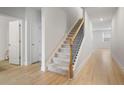 Hallway with light wood floors leads to stairs with carpet, featuring white walls and doors at 5 Dew Drop Pt, Dallas, GA 30157
