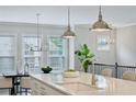 Kitchen island detail with sink, modern pendant lighting, quartz countertops, and hardwood floors at 1165 Millennium Park Rd, Decatur, GA 30033