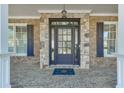 Elegant front entrance with a detailed glass door, stone accents, and a covered porch area at 2546 Summer Song Way, Buford, GA 30519