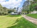 A quaint one-story home with a gravel driveway, a carport, and a well-manicured lawn at 1202 Coan Dr, Locust Grove, GA 30248