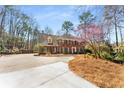 Classic brick home with an extended driveway complemented by mature trees and flowering bushes at 9835 Trace Vly, Sandy Springs, GA 30350