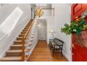 Elegant foyer with hardwood floors, a staircase, chandelier, and a red front door adorned with a floral arrangement at 9835 Trace Vly, Sandy Springs, GA 30350