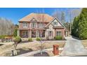 Elegant brick home featuring mature trees, a well-kept lawn, and a paved driveway at 3149 Hidden Falls Ne Dr, Buford, GA 30519
