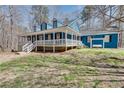 Blue home with a long porch and manicured lawn surrounded by a beautiful forest at 2970 Oxford Rd, Atlanta, GA 30349