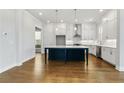 Elegant kitchen showcasing a spacious island, white cabinets, stainless steel appliances, and hardwood floors at 630 Silva St, Cumming, GA 30040
