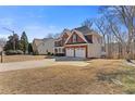 Brick home with a two-car garage has mature trees in the yard on a sunny day at 3967 Bellingrath Main Nw, Kennesaw, GA 30144