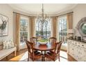 Charming dining room with bay window views and a stylish chandelier over the wood table at 1100 Muirfield Ct, Alpharetta, GA 30005