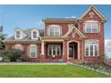 Two-story brick home featuring dormer windows and a covered front porch with manicured lawn at 2220 Stirling Bridge Rd, Cumming, GA 30041