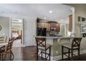 An open kitchen features dark wood cabinets, granite counters and stainless appliances with bar stool seating at 115 Dorys Way, Dallas, GA 30157