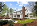 Spacious backyard with a large patio, outdoor fireplace, lush greenery, and a manicured lawn at 12680 Old Surrey Pl, Roswell, GA 30075