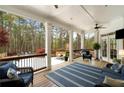Inviting covered patio with comfortable seating, ceiling fan, outdoor fireplace, and a view of the wooded backyard at 12680 Old Surrey Pl, Roswell, GA 30075