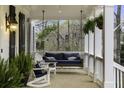 Inviting covered front porch with brick flooring, hanging swing, chairs, and decorative plants for outdoor enjoyment at 12680 Old Surrey Pl, Roswell, GA 30075