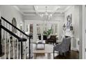 Bright living room featuring coffered ceilings, a fireplace, hardwood floors, and staircase with stylish decor at 12680 Old Surrey Pl, Roswell, GA 30075