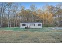 Single-story home surrounded by trees and an ample front yard with a trashcan on the side at 355 Double D Rd, Temple, GA 30179