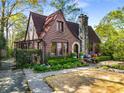Attractive brick Tudor-style home with a stone chimney, featuring a well-maintained lawn and professional landscaping at 1620 N Pelham Ne Rd, Atlanta, GA 30324