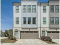 Modern townhome featuring a gray and white exterior, brick accents, a two-car garage, and professional landscaping at 6187 Kelly Carlin Way, Norcross, GA 30071