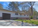 Side view of a home shows the driveway leading to the attached garage and the well-manicured lawn at 3016 Deshong Dr, Stone Mountain, GA 30087