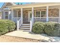 Close up of a house showing a charming front porch with stone detailing, white pillars, and neatly trimmed bushes at 189 Meadow Spring Dr, Temple, GA 30179