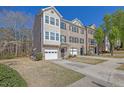 Well-maintained townhome with a one-car garage, manicured lawn, and mature trees at 2138 Mill Garden Run, Buford, GA 30519