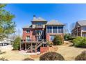 Back of home featuring a wooden deck, screened porch, brick patio, and landscaped yard at 1037 Windermere Xing, Cumming, GA 30041
