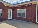 Brick home exterior with a concrete patio, an awning, and multiple windows for natural lighting at 1705 Rolling View Dr, Cumming, GA 30040