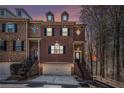 Charming brick townhome at dusk featuring a two-car garage and inviting front entrance with black iron railings at 600 Jardin Ct # 48, Alpharetta, GA 30022