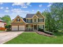 Charming two-story home featuring a manicured lawn, brick accents, a two-car garage, and traditional architectural details at 5815 P.W.A. Dr, Cumming, GA 30041
