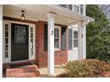 Inviting front porch with brick accents, white columns, and a stylish front door at 802 Eagle Glen Xing, Woodstock, GA 30189