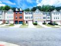 Street view showcases well-maintained townhomes, each with unique brick and siding designs and individual garages at 523 Lantern Wood Dr, Scottdale, GA 30079
