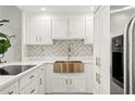 This kitchen features pristine white cabinetry, a stylish backsplash, stainless appliances, and a golden farmhouse sink at 130 26Th Nw St # 807, Atlanta, GA 30309