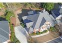 An aerial view of a brick home with a spacious driveway, landscaped yard and well-maintained roof at 9175 Etching Overlook, Johns Creek, GA 30097