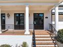 Close-up of the beautiful front porch with columns, brick steps and black railings, and double doors at 3020 Barnes Mill Ct, Roswell, GA 30075