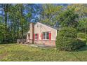 Charming home featuring red shutters, a brick base, and a cozy front porch, surrounded by lush greenery and mature trees at 5520 Glore Sw Dr, Mableton, GA 30126