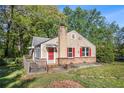 Charming home featuring red shutters, a brick base, and a cozy front porch, surrounded by lush greenery and mature trees at 5520 Glore Sw Dr, Mableton, GA 30126