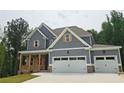 Attractive two-story home with covered front porch and three-car garage and classic gray siding at 174 Pinewood Dr, Covington, GA 30014