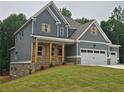 Two-story home with a covered front porch, gray siding, and a three-car garage at 174 Pinewood Dr, Covington, GA 30014