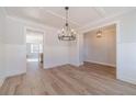 Neutral interior of the house with a modern chandelier illuminating wood-look floors, and trim with paneled walls at 174 Pinewood Dr, Covington, GA 30014