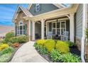 Inviting front porch with rocking chairs, lush landscaping, and stone accents at 161 Dorys Way, Dallas, GA 30157