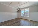 Elegant dining room with wood-look flooring, wainscoting, coffered ceiling, and stylish chandelier fixture at 210 Pinewood Dr, Covington, GA 30014