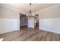Elegant dining room with wood-look floors leading to a staircase and featuring stylish wainscoting at 210 Pinewood Dr, Covington, GA 30014