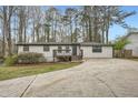 Charming single-story home with a gray exterior, inviting front porch, and a long driveway surrounded by mature trees at 4953 Apple Valley Rd, Douglasville, GA 30135