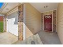Covered entryway featuring a red front door, brick accents, and a view of the attached garage at 520 Crick Pt, Palmetto, GA 30268