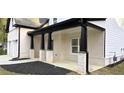Covered porch with black columns, brick accents, and lush landscaping create inviting outdoor space at 355 Hilltop Cir Sw Ext, Mableton, GA 30126