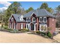 Stately brick home with a manicured lawn, dark shutters and black roof presents a welcoming and attractive curb appeal at 3795 Duckcove Way, Cumming, GA 30041