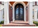 Close-up of elegant black arched front door, flanked by brick columns and beautiful trim at 3795 Duckcove Way, Cumming, GA 30041