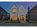Charming two-story home with white brick, an arched entry, manicured landscaping, and a warm, inviting glow at dusk at 250 4Th St, Fayetteville, GA 30214