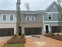 New townhome boasts a gray and brick facade, open garages, and well-maintained landscaping at 113 Priestwood Ln, Acworth, GA 30102