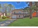 Traditional two-story home with an attached garage, lush green lawn, and mature trees in a serene setting at 1045 Forest Path, Stone Mountain, GA 30088