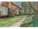 Charming red brick townhome featuring a bay window, walkway, and mature trees at 1384 Sheffield Glen Ne Way, Atlanta, GA 30329